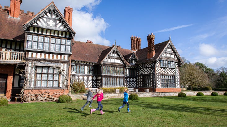 Three children are running across the South Terrace lawn at Wightwick Manor.